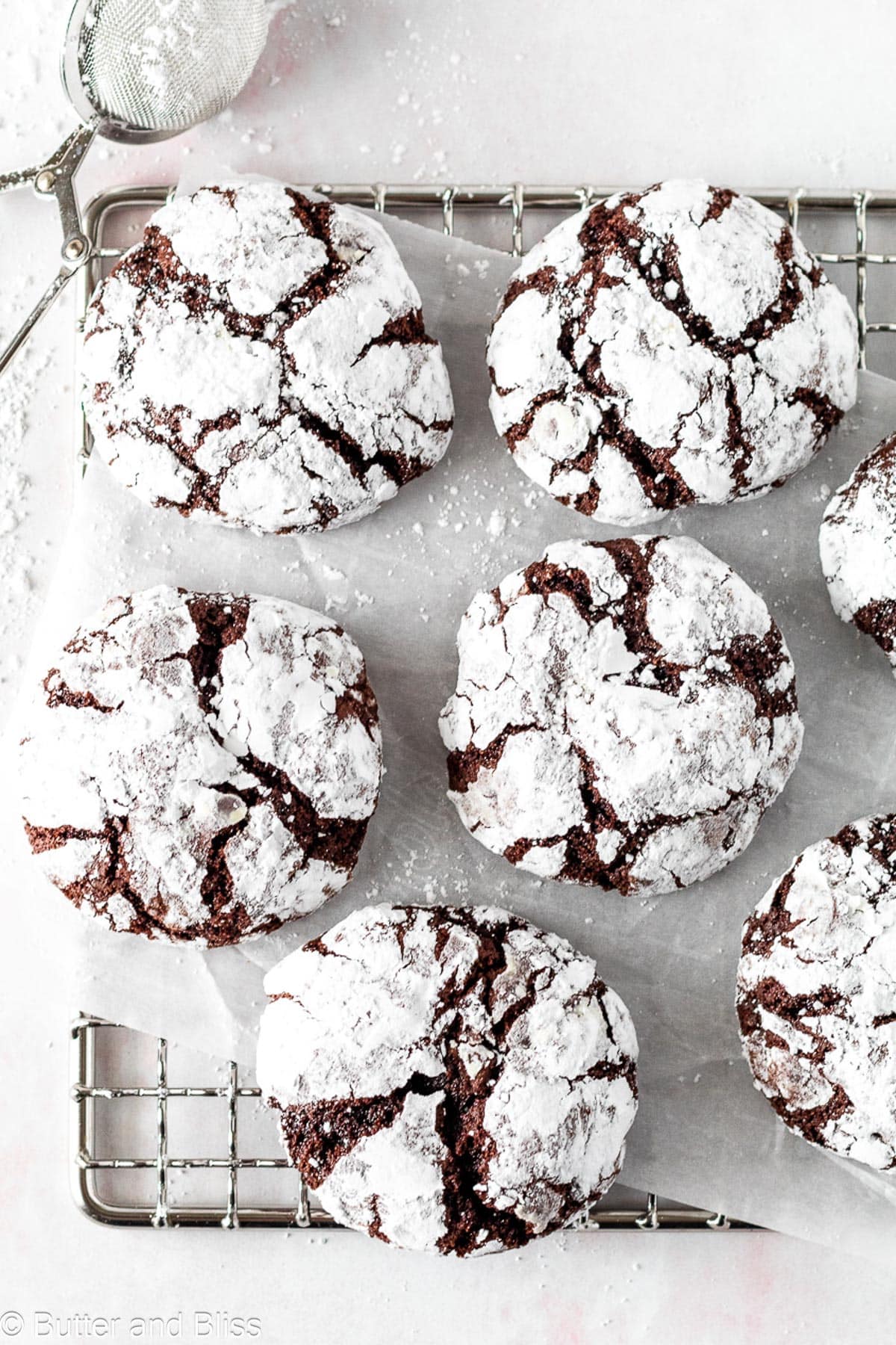 Small batch chocolate crinkle cookies with powdered sugar on a wire cooling rack.
