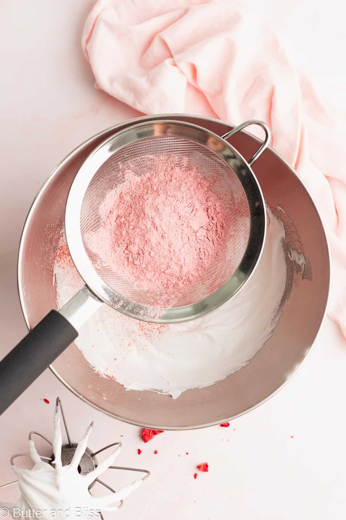 Freeze-dried strawberries sifted over a bowl of dairy free cream.