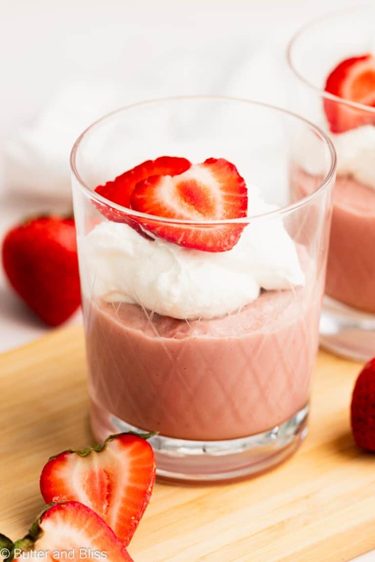 Pretty pink strawberry pudding for two in serving glasses and topped with whipped cream.