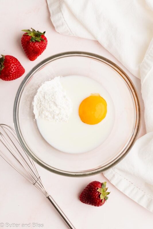 Milk, egg yolk, and cornstarch in a mixing bowl with a whisk.