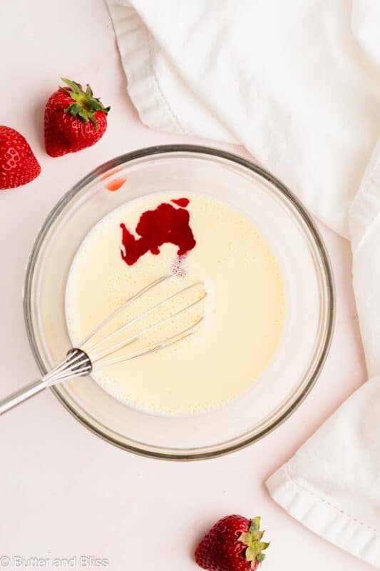 Heated strawberry puree poured into a mixking bowl of corn starch slurry.