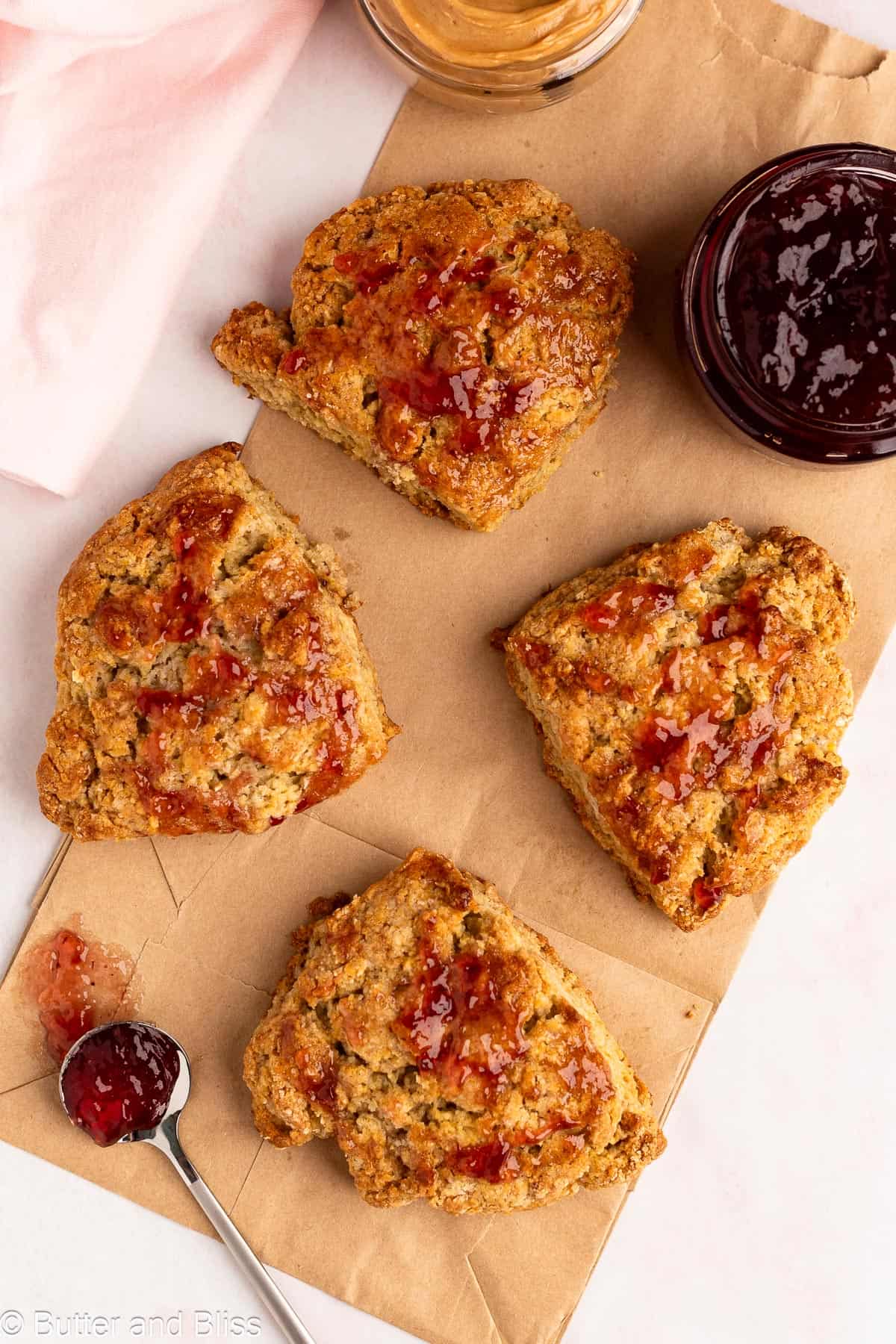 Small batch scones brushed with jam on a paper bag.