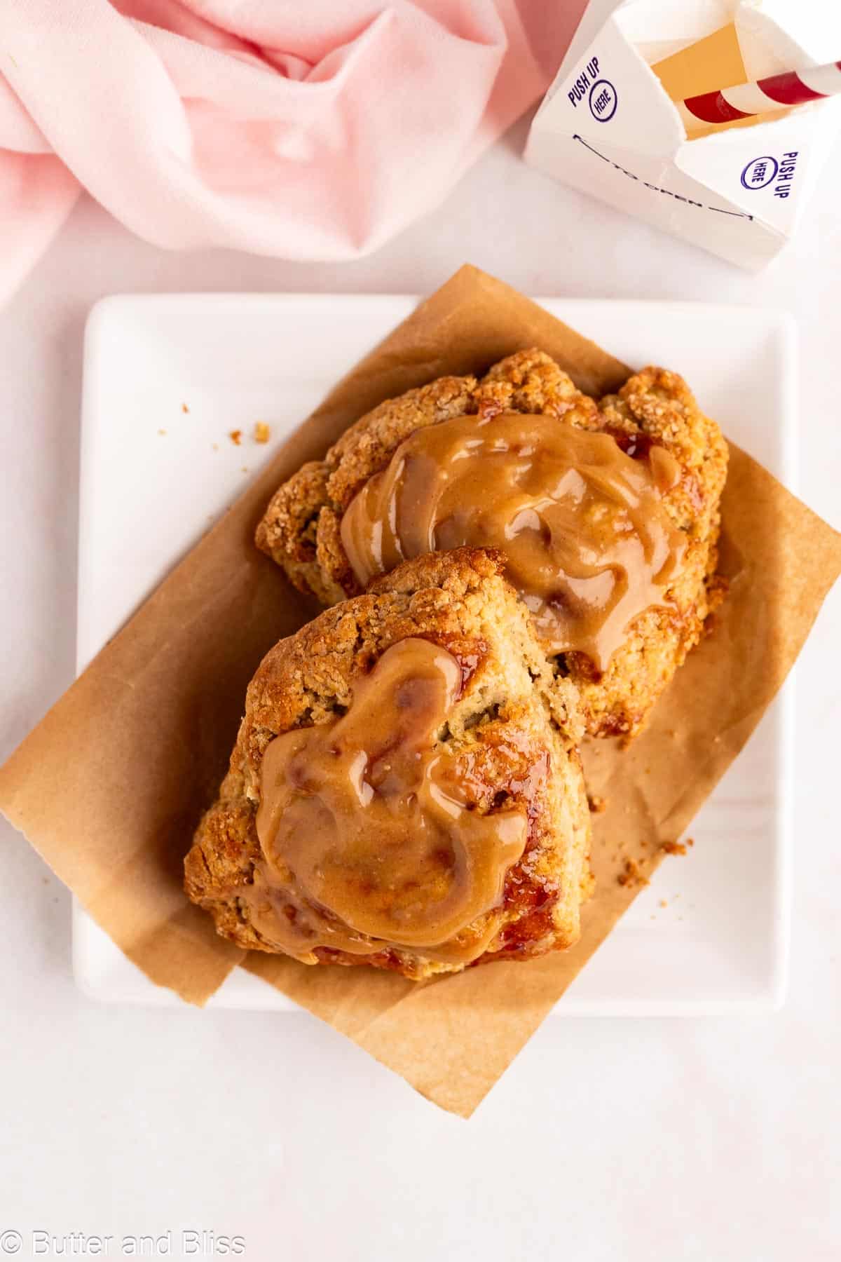 Jam scones with peanut butter glaze on a white plate.