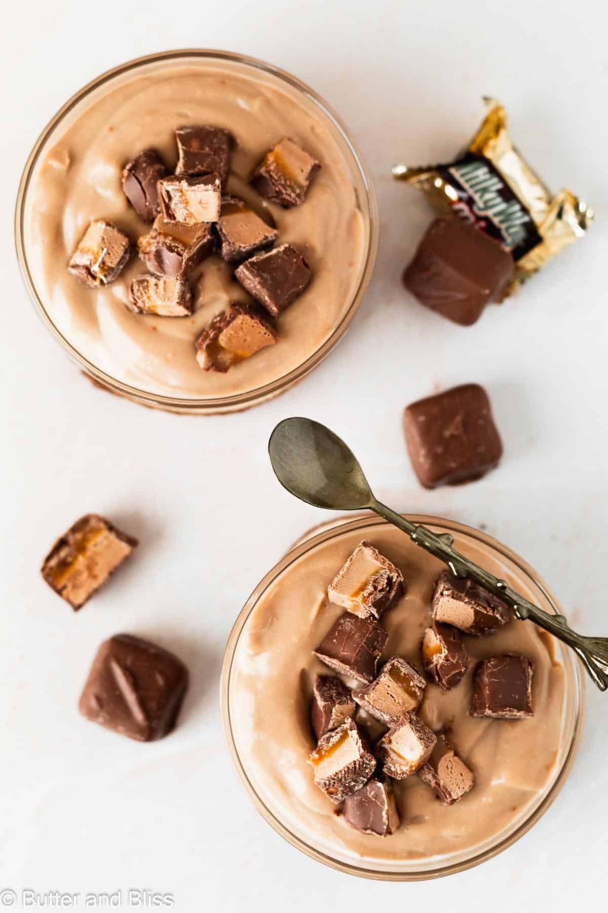 Individual bowls of chocolate pudding with chocolate caramel candy pieces on top.