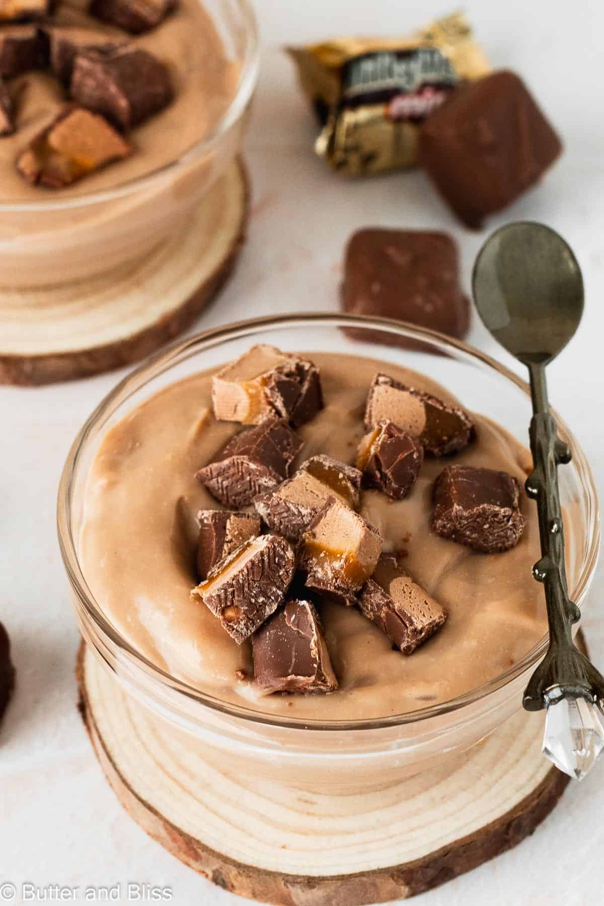 Milky way chocolate pudding in a small bowl and topped with candy pieces.