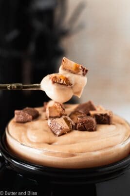 Creamy milky way pudding on a small spoon with pieces of candy on top.