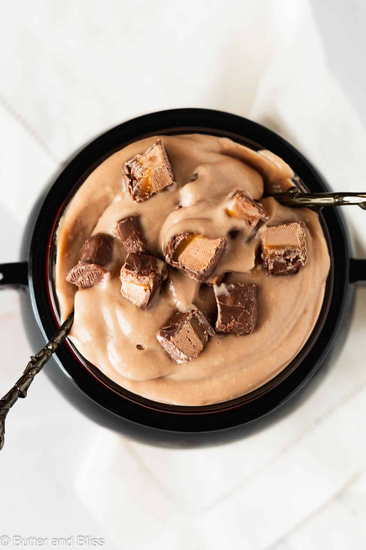 Chocolate caramel Halloween candy chocolate pudding in a bowl topped with candy pieces.