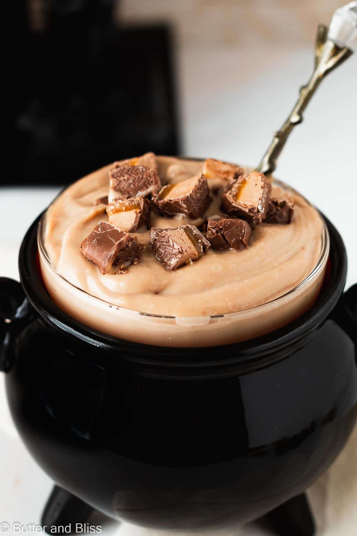 Milky way chocolate pudding in a Halloween bowl topped with candy pieces.