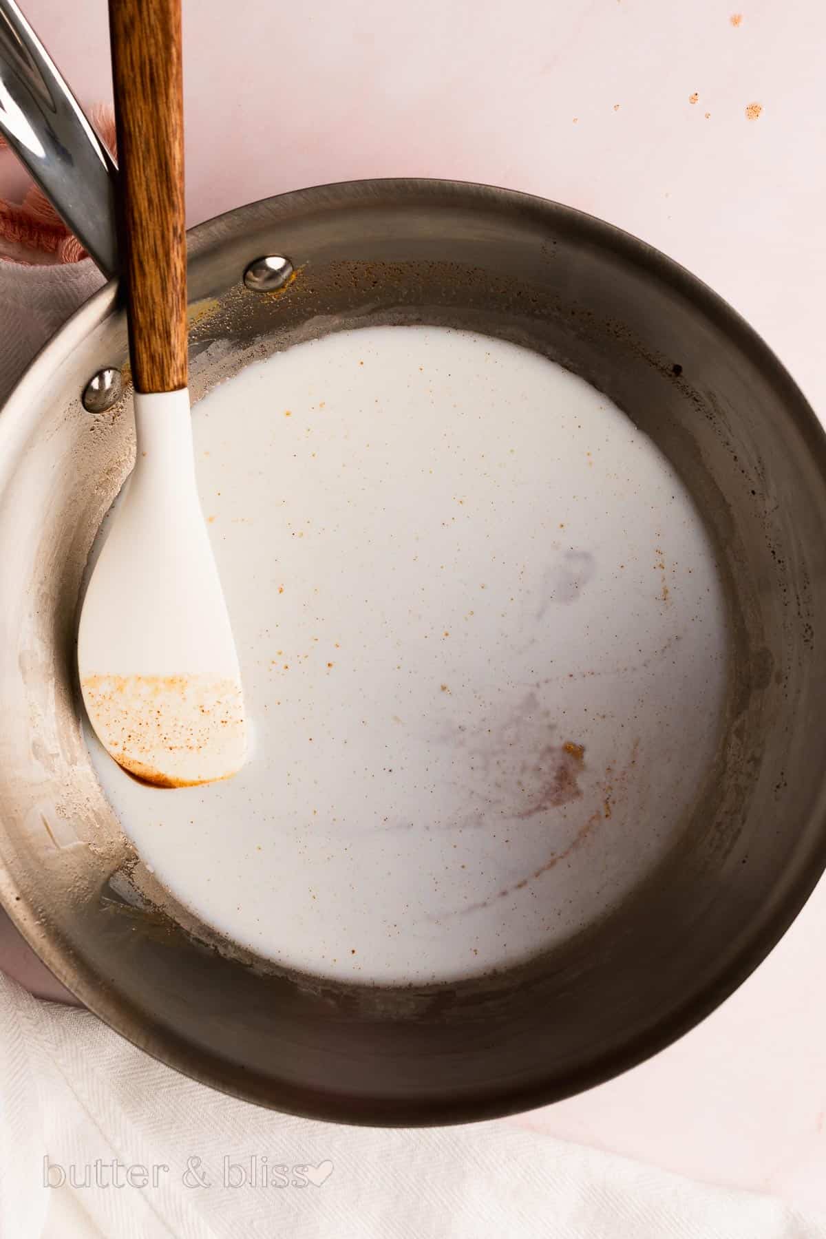 Milk being warmed in a small saucepan.