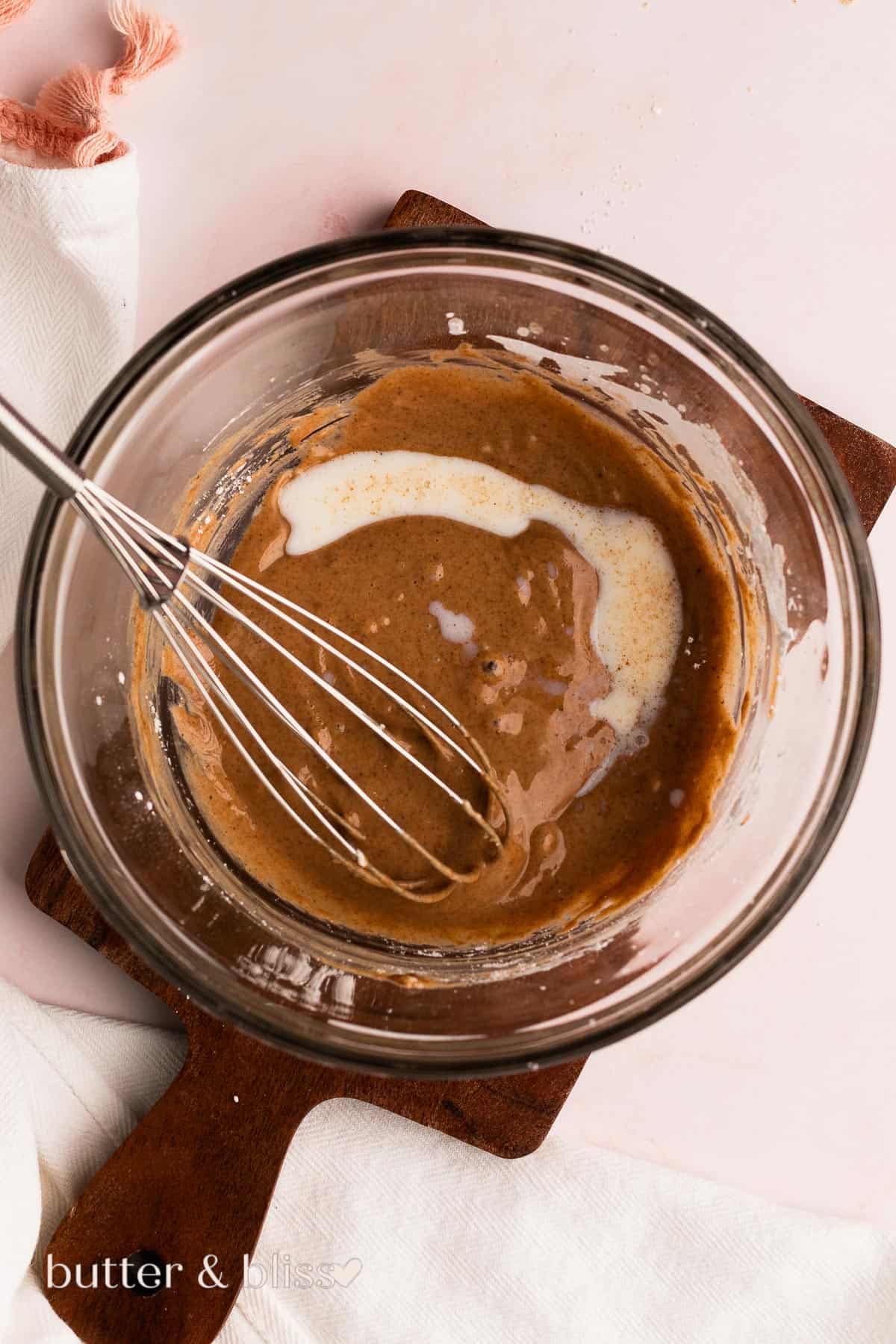 Fall pastry glaze ingredients being mixed a mixing bowl with whisk.