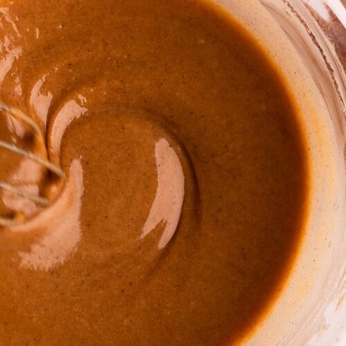 Brown butter and cinnamon flecks in silky fall icing in a bowl.