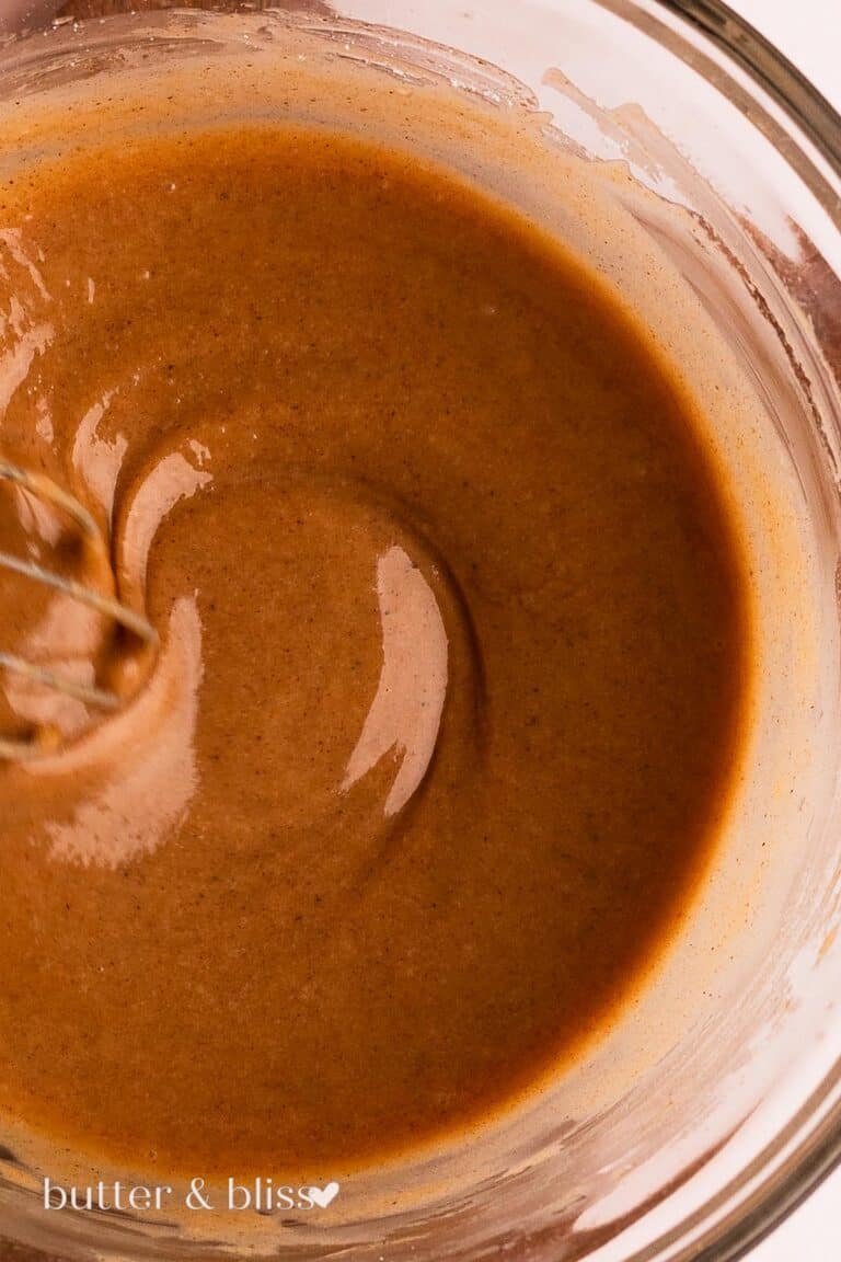 Brown butter and cinnamon flecks in silky fall icing in a bowl.