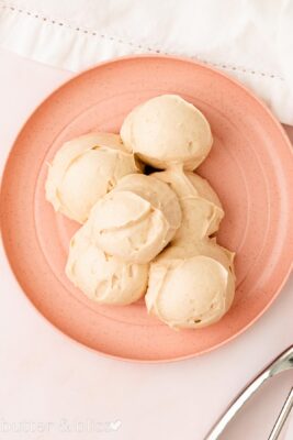 Scoops of cinnamon maple fluffy frosting on a pink plate.