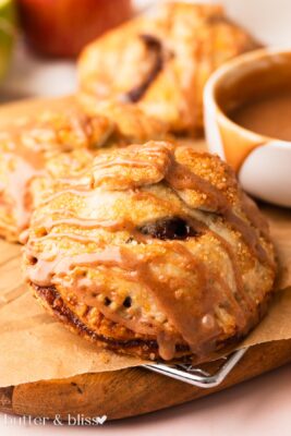 Apple hand pie with buttery glaze on a wood plate.