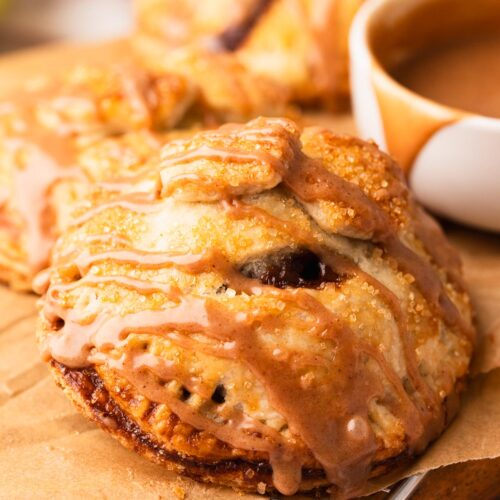 Apple hand pie with buttery glaze on a wood plate.