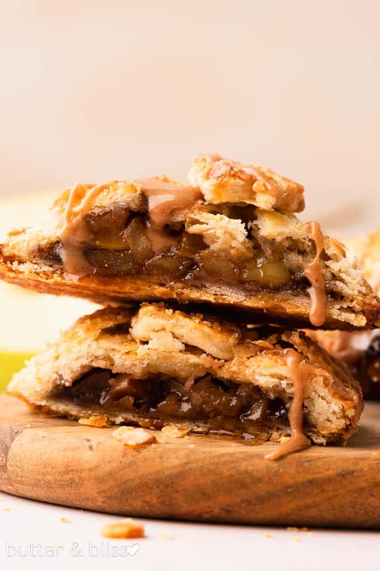 Apple brown sugar hand pie cut in half on a cutting board revealing bubbly apple filling.