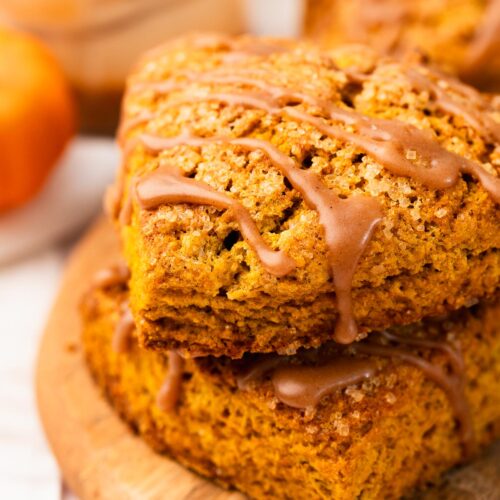 Two pumpkin scones stacked and drizzled with brown butter cinnamon glaze.