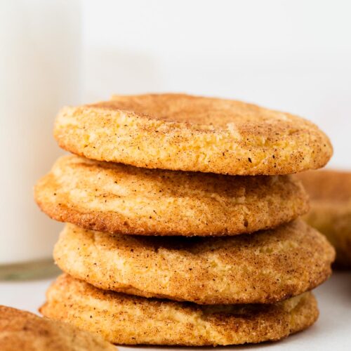 Stack of snickerdoodle cookies next to a glass of milk.