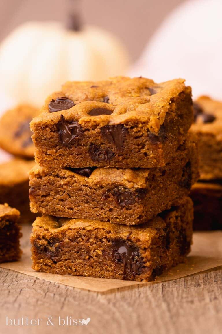 A stack of pumpkin chocolate chip cookie bars on a wood table.