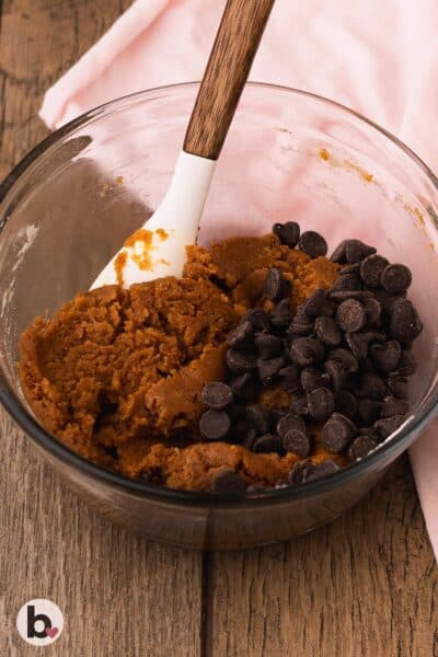 Thick pumpkin cookie bar dough with added chocolate chips in a mixing bowl.