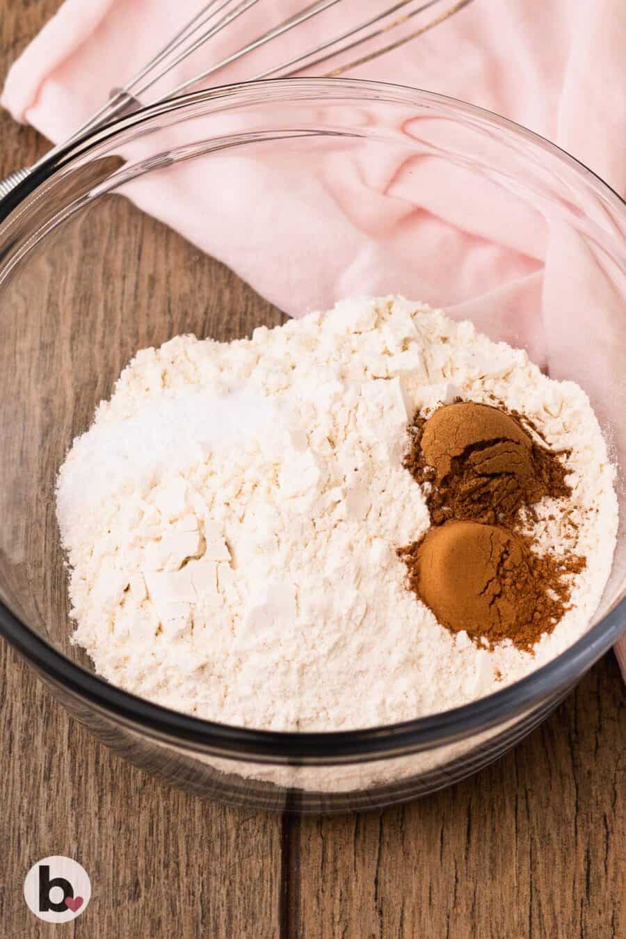 Flour and spices in a mixing bowl next to a pink napkin.