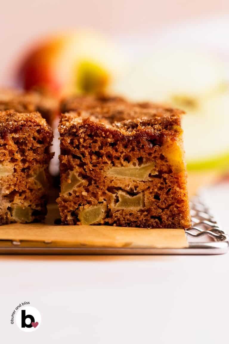 Chunks of apple inside a slice of apple spice cake on a wire cooling rack.