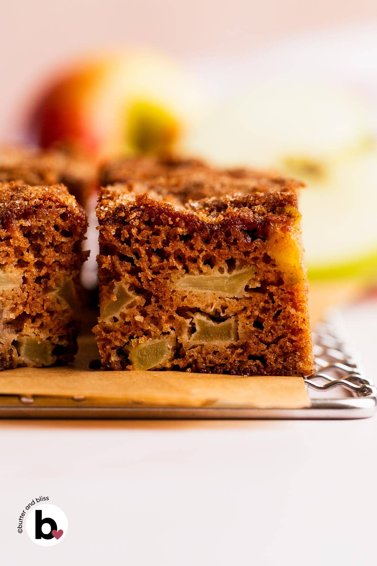 Chunks of apple inside a slice of apple spice cake on a wire cooling rack.