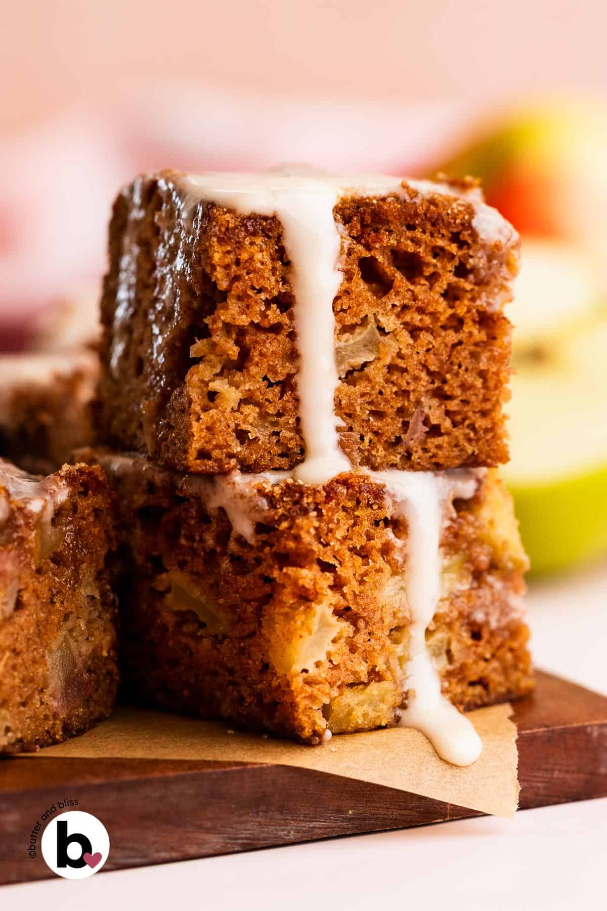 Two squares of chunky apple spice cake stacked and drizzled with icing.