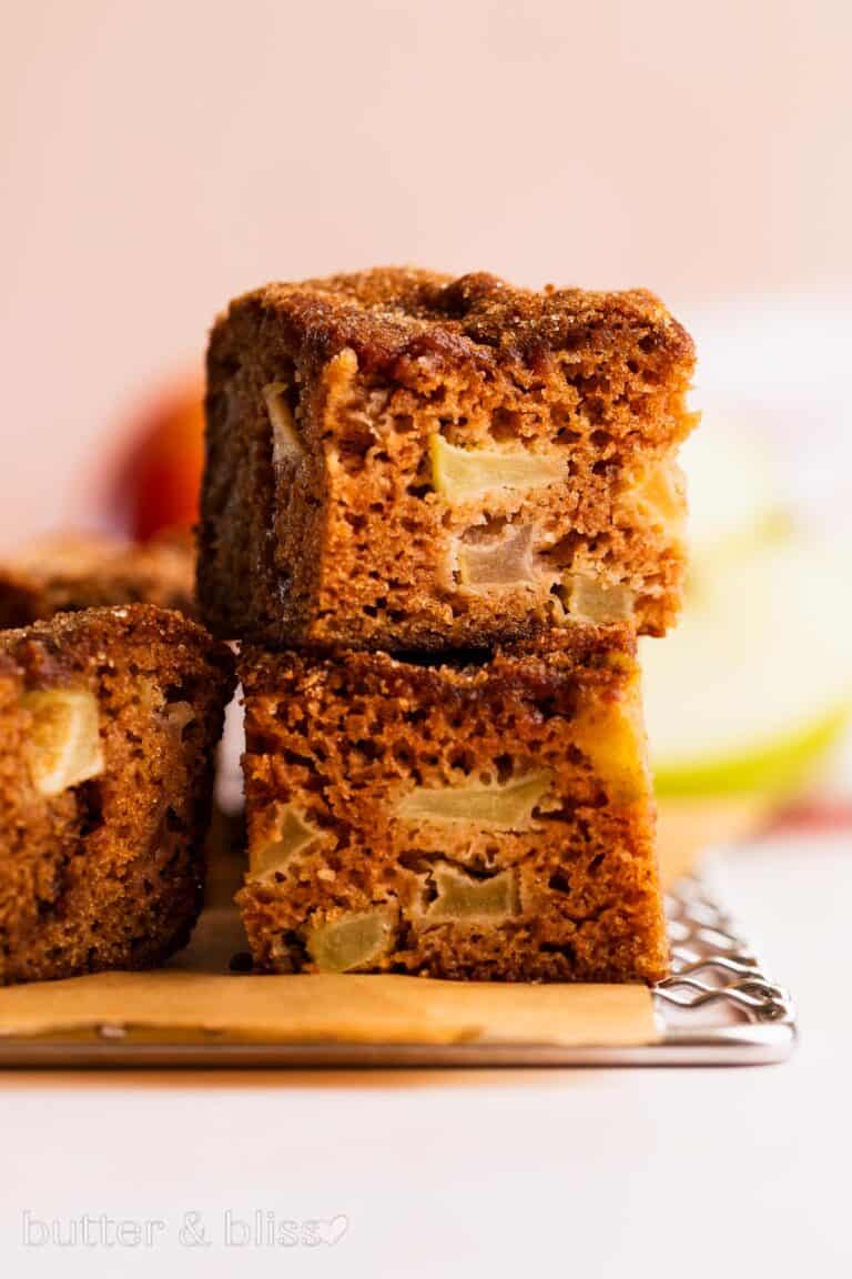 Chunky apple cake slices stacked on a wire cooling rack.