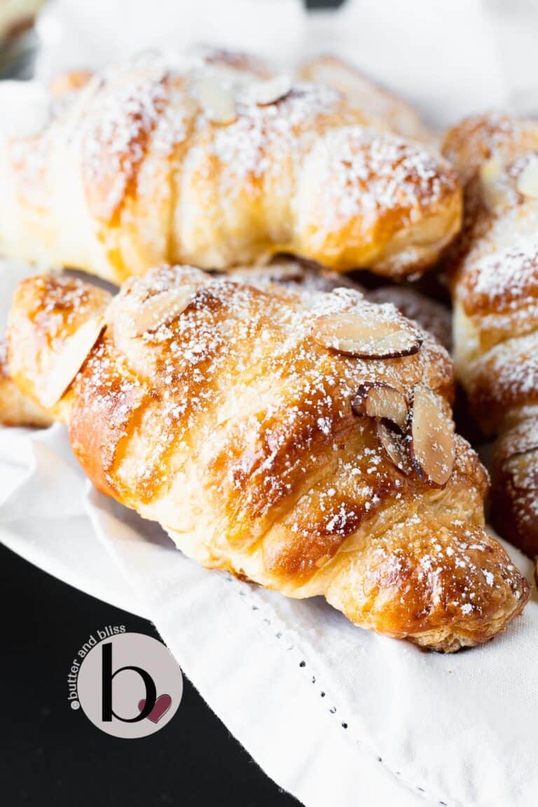 Almond croissants dusted in powdered sugar in a basket.