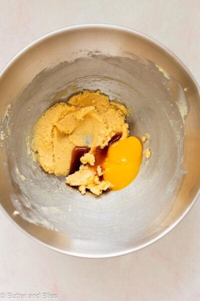 Egg yolk added to creamed butter and sugar in a mixing bowl.