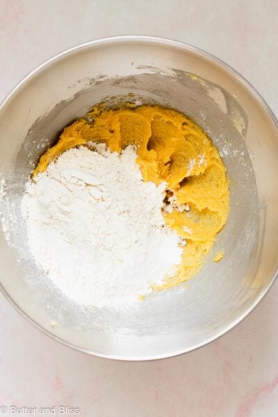 Dry ingredients added over creamed butter and sugar in a mixing bowl.