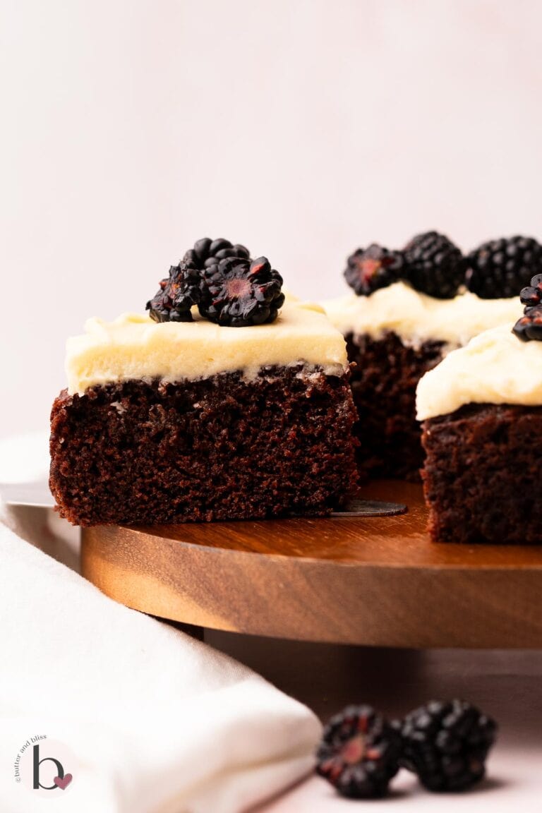 Moist slice of chocolate cake with vanilla frosting and fresh blackberries.