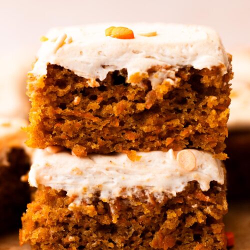 Two carrot cake bars stacked on top of eachother and finished with frosting.