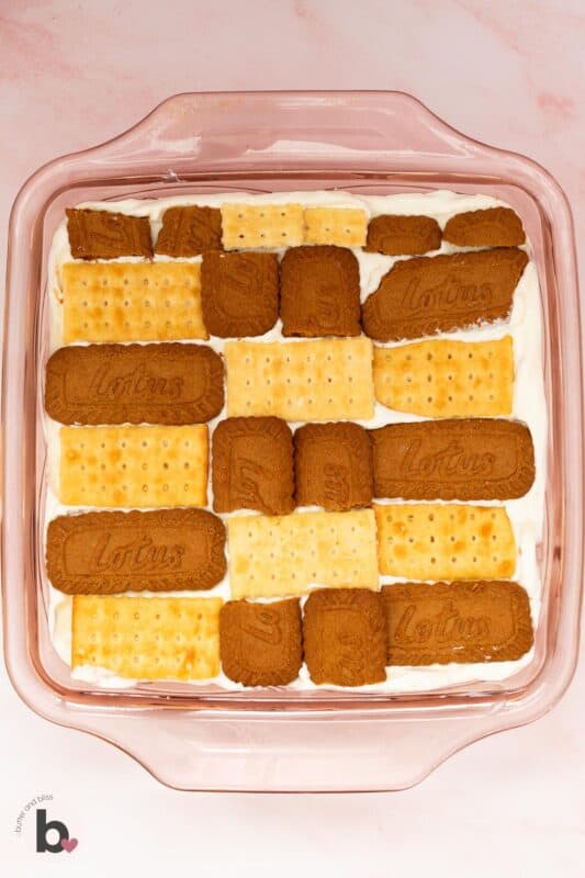 Sweet and savory crackers layered on top of whipped cream in a baking dish.