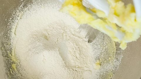 Flour added to creamed butter in a mixing bowl.
