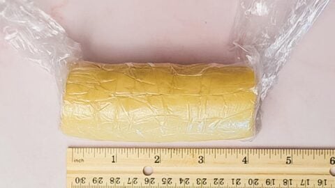 Lemon shortbread dough rolled into a log and measured with a ruler.
