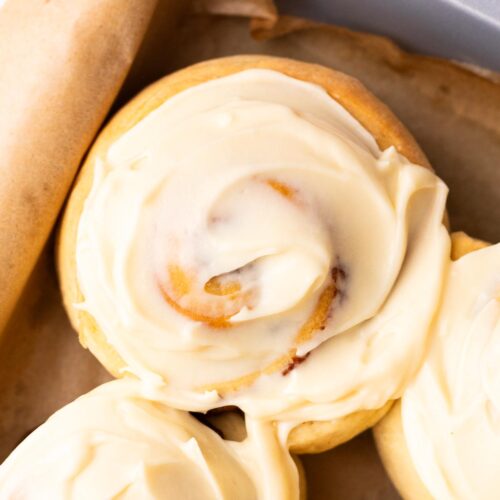 Thick cream cheese icing swirled on top of fresh baked cinnamon rolls.