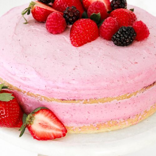 Layered mousse genoise cake with fresh berries on a cake stand.