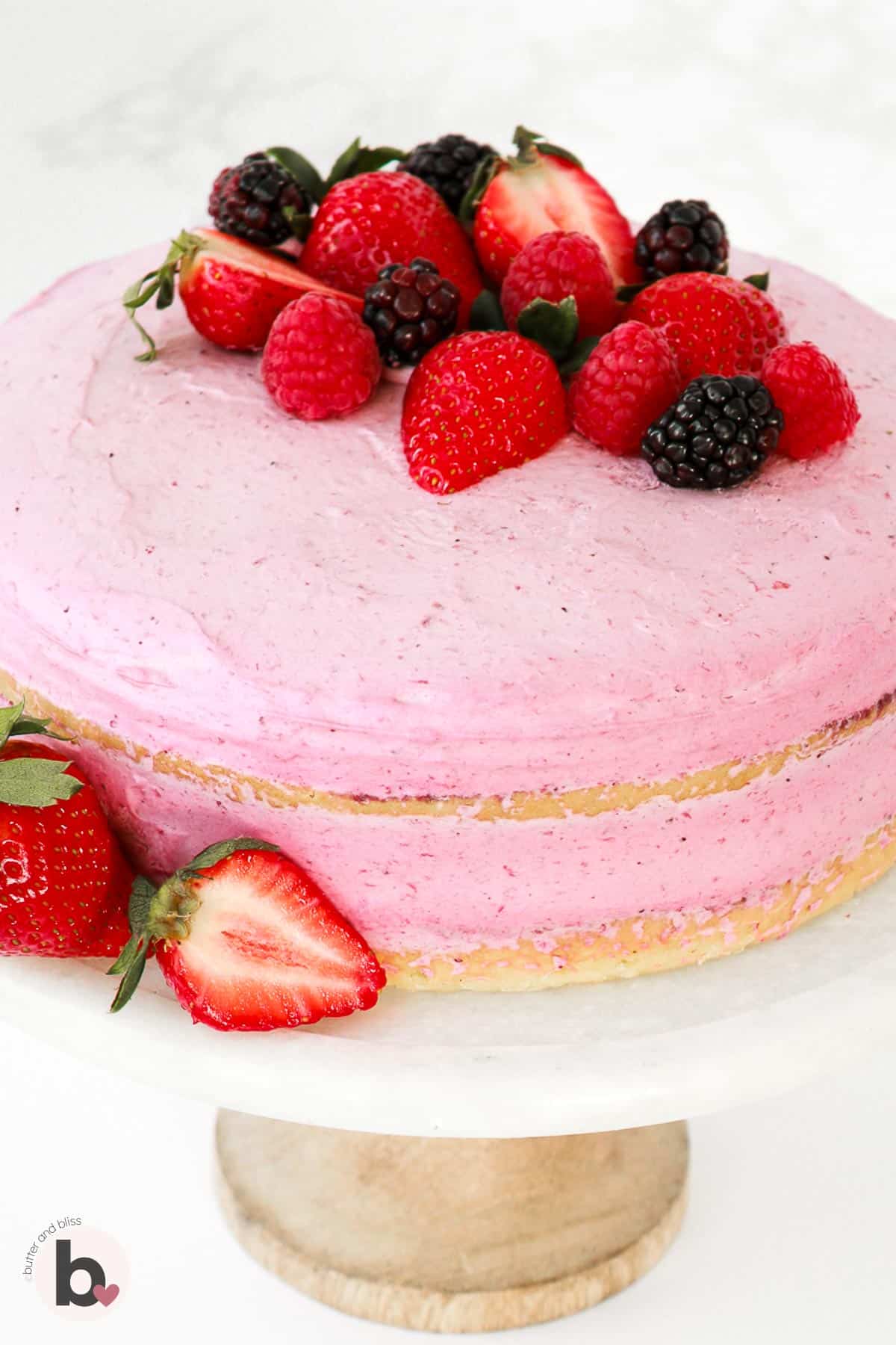 Layered mousse genoise cake with fresh berries on a cake stand.
