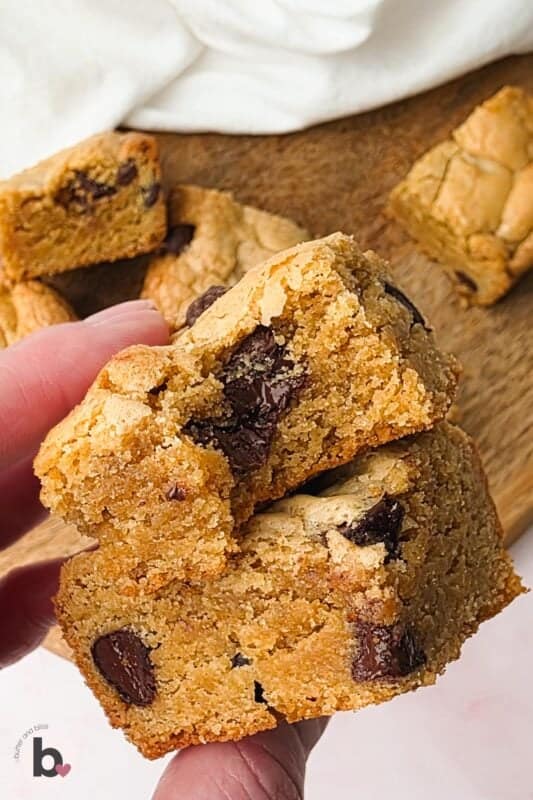 Erin holding two blondie squares with a bite out of one.