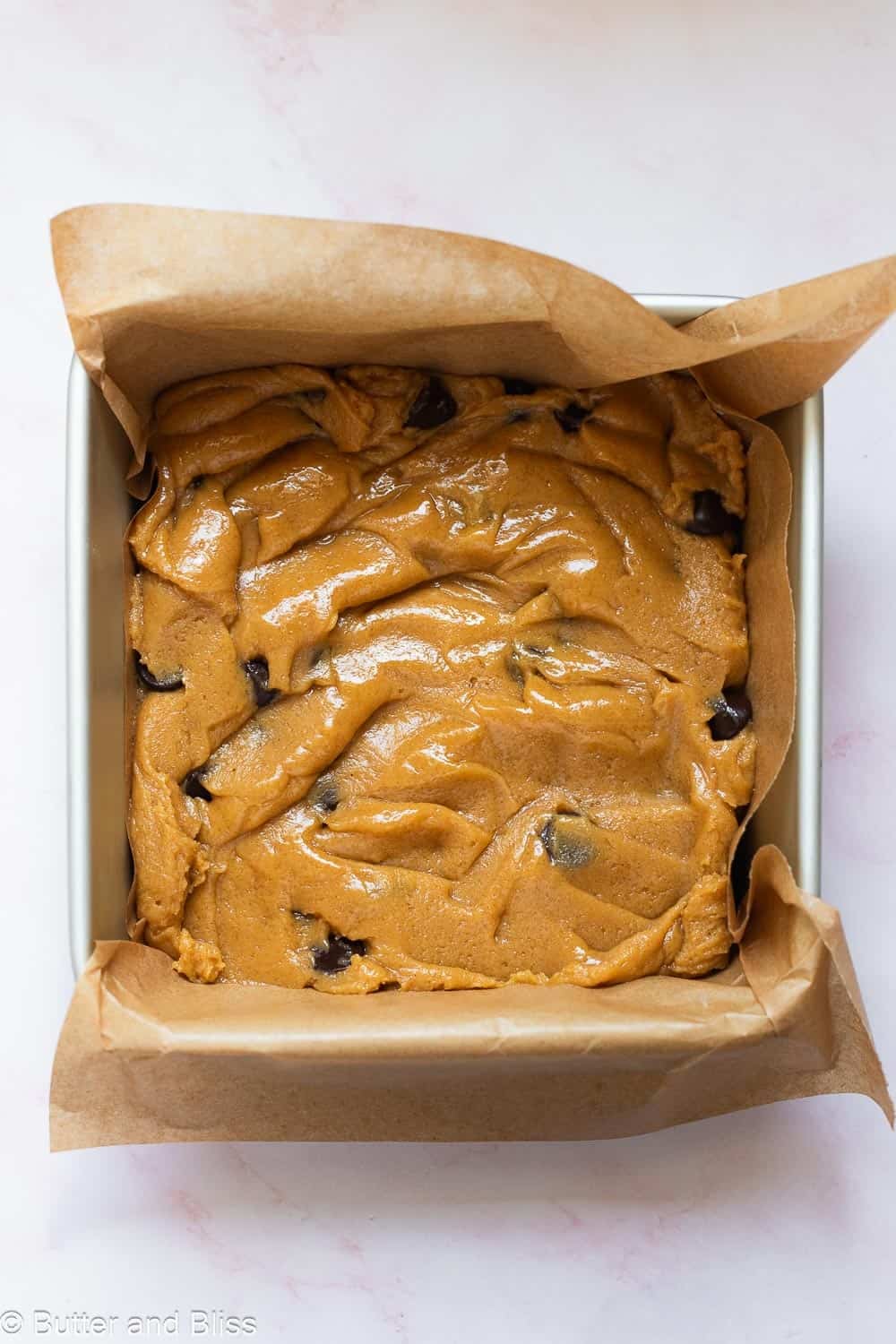 Thick blondie batter with chocolate chips pressed into a small pan.