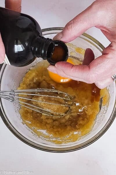 An extra splash of vanilla added to blondie batter in a bowl.