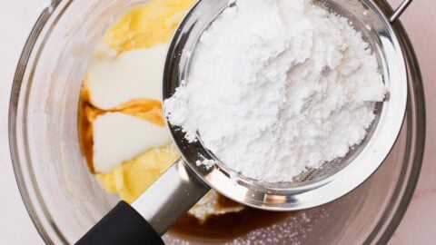 Powdered sugar sifted into a bowl of creamed butter.