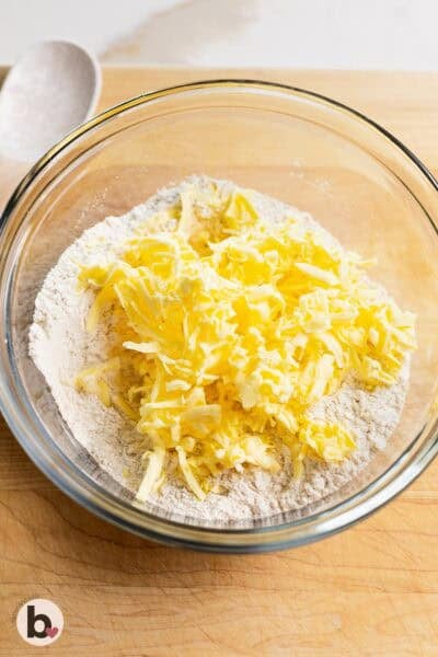 Grated butter added to a bowl of dry ingredients.