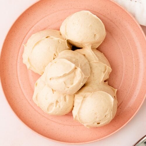Scoop of cream cheese frosting on a pink plate.