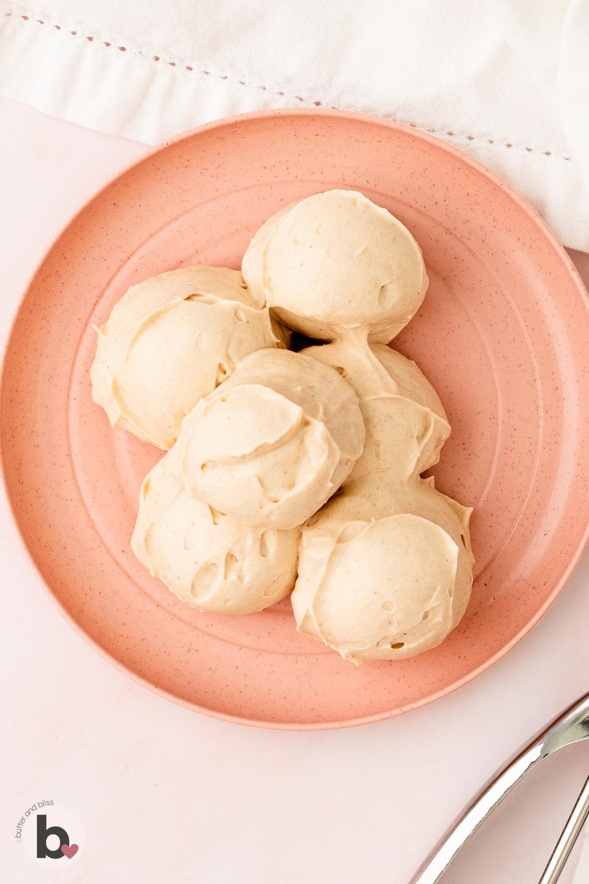 Scoop of cream cheese frosting on a pink plate.