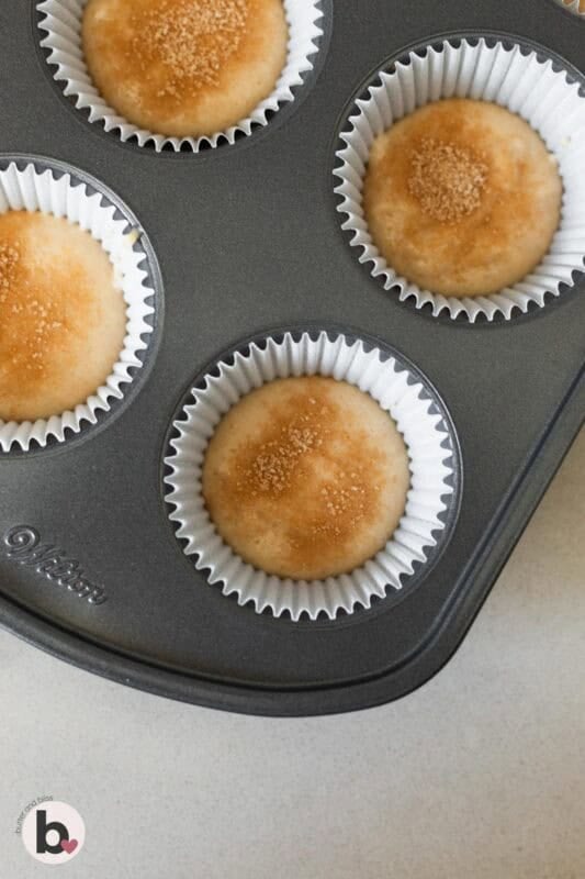 Cinnamon sugar sprinkled on top of cupcake batter in liners.