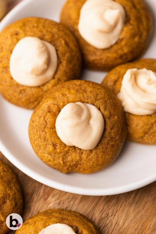 Pumpkin thumbprint cookies with creamy filling on a plate.