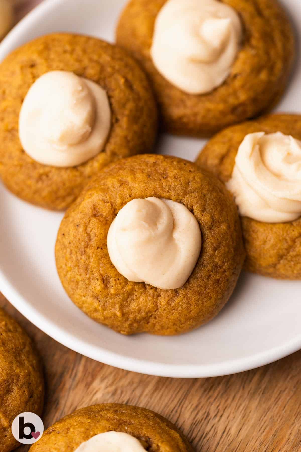 Pumpkin thumbprint cookies with creamy filling on a plate.